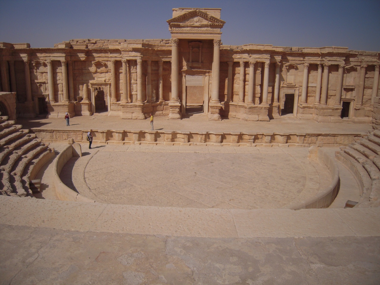 Figure 12: Images from the Palmyra theater before and after the bombing of the façade of the theater. Photo by Hassan Ali 2011, Zaher Al-Saleem 2024